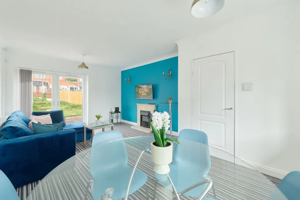 Bright living and dining room with a sofa, glass dining table and garden doors